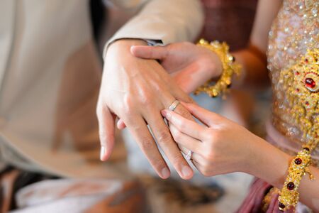 Bride and Groom putting wedding ring on finger, Thai wedding engagement ceremonyの写真素材