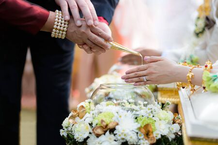 Holy water pouring ceremony over bride and groom hands, Thai traditional wedding engagementの写真素材