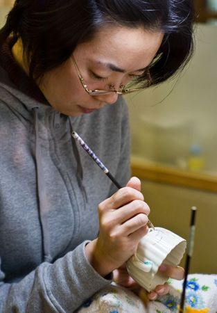 Miyama, Kagoshima, Japan, November 2nd 2008. A Japanese woman painting a design onto white Satsuma ware pottery.のeditorial素材