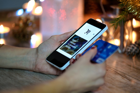 Woman makes Christmas shopping via smartphone and a credit card in the online storeの写真素材