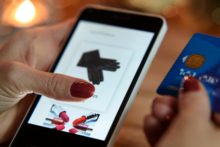 Modern Woman makes shopping via smartphone and a credit card in the e-storeの写真素材