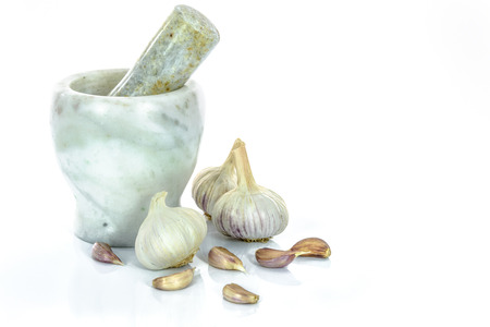 Garlic bulbs and cloves with marble mortar and pestle isolated on a white background.の写真素材