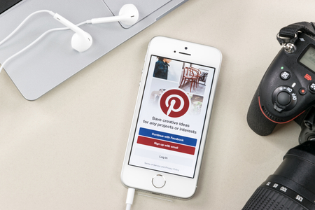 Krynica, Poland - February 02, 2017: Pinterest app on iPhone SE, close to a laptop and Nikon DSLR camera. Pinterest is one of the most popular social media content sharing service app on the world.のeditorial素材