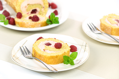 Delicious homemade roll cake with raspberry filling sprinkled with powdered sugar and raspberries and mintの写真素材