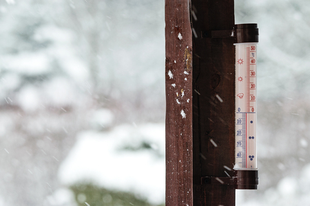 Concept image of winter coming - thermometer outside the house indicates below zero and it is snowing heavily.の写真素材