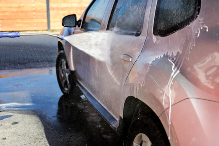 Washing car under high pressure with water and shampoo in close-upの写真素材