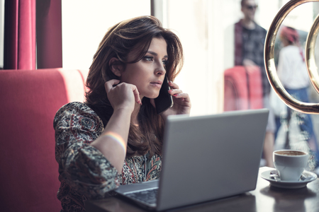 Beautiful young business woman working while drinking coffee in the restaurant.の写真素材