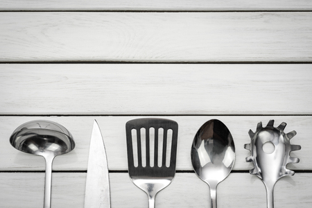 Top view of a silver kitchen utensil collection on a wooden table with copy space.の写真素材