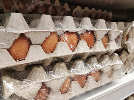 Containers with chicken eggs on the shelves for sale in the supermarket.