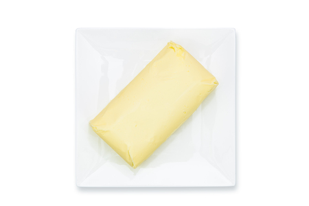 Top view of fresh organic butter block on the plate isolated on a white background in close-upの写真素材