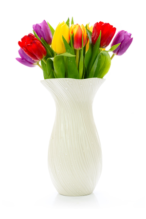 Fresh multi colored tulips flowers in a vase isolated on a white backgroundの写真素材