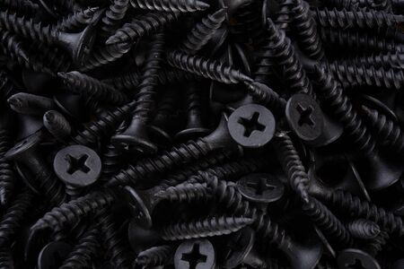 Full frame textured background  - pile of new metal black screws in close-upの写真素材
