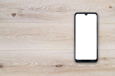Top view of a new modern black frameless smartphone mockup with blank white screen on a wooden table...