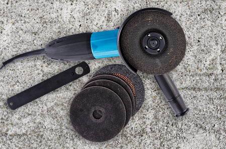 Top view of an angle grinder on concrete floor with accessories