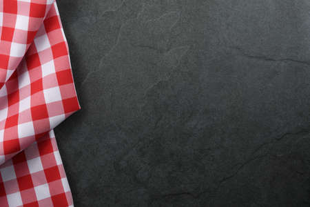 Classic italian cooking background - red checkered tablecloth on a vintage black stone kitchen countertop with copy spaceの写真素材