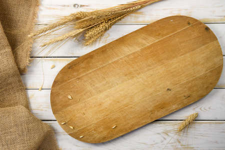 Rustic baking template - top view of an empty wooden cutting board with cereal grains and burlap...