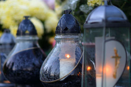 Concept of passing away - close up of burning candles on a grave as a memory of a deceased person.