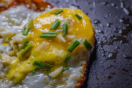 fried eggs with onion and chives on a black background, top viewの写真素材