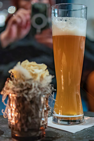 A glass of beer on a table in a pub, with a blurred backgroundの写真素材
