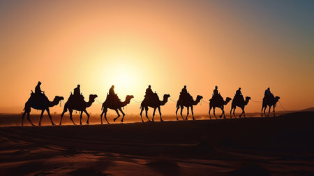 A caravan of Egyptians gracefully rides camels through the vast desert, of the setting sunの素材