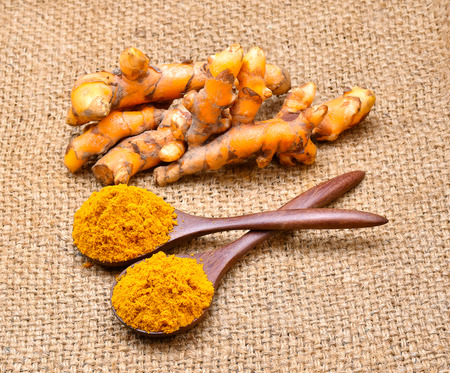 Turmeric and turmeric powder on wooden background