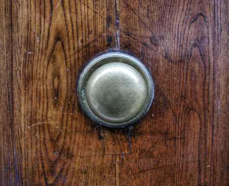 Brass door knob in the centre of the old italian wooden door. Close up.の写真素材