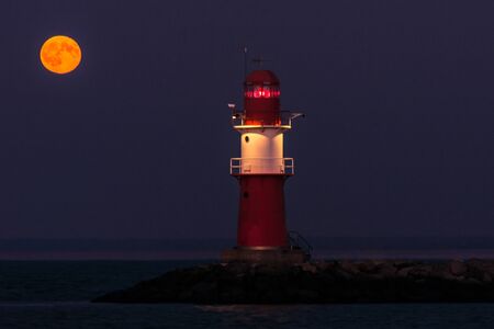Lighthouse on the east pier in Warnemünde under a full moonの写真素材