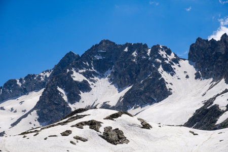 Breathtaking view of snow-covered peaks towering over a rocky terrain in Vermiglio, Italy highlights the beauty of nature under clear blue skis.の写真素材