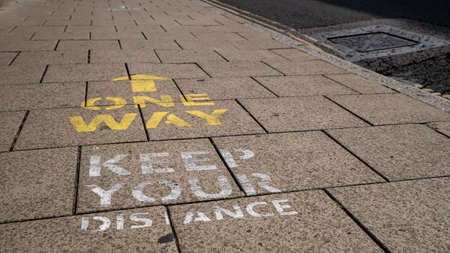 Keep your distance and one way signs painted onto a pavement in Oxford as part of social distancing measuresの写真素材