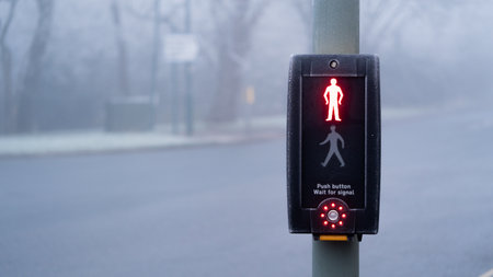 UK traffic crossing with Red man and crossing button Illuminated on a cold foggy day