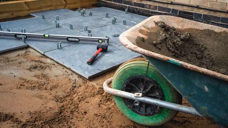 Patio being laid with tools and wheelbarrow full of concrete