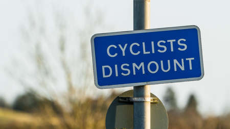 Blue Cyclists Dismount sign in a park