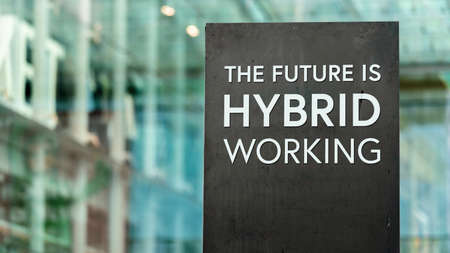 The Future of Work is Hybrid sign in front of a modern office buildingの写真素材