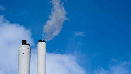 Smoke from chimney tower against cloudy skyの写真素材