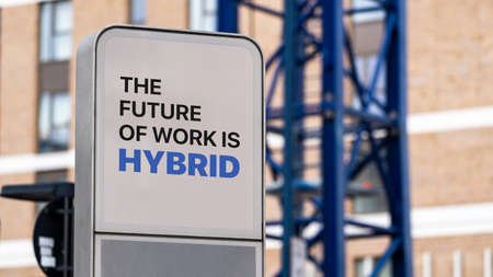 The Future of work is Hybrid on a city-centre sign with a construction crane in backgroundの写真素材