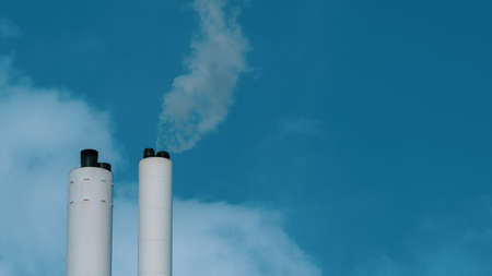 Smoke from chimney set against a blue skyの写真素材
