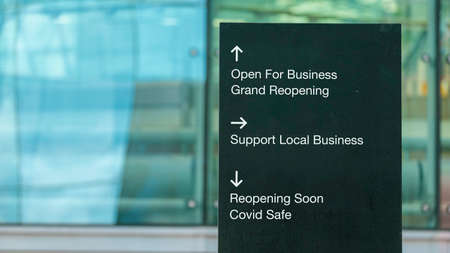 Open for business words used on a city-center sign in front of a modern office buildingの写真素材