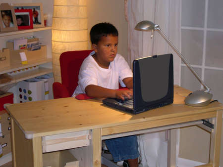 Boy using laptop at desk.の写真素材