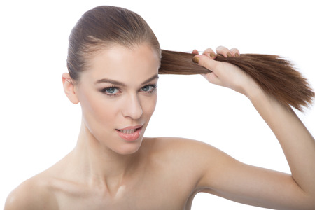 Beautiful woman pulling her long straight hair,over white backgroungの写真素材