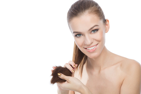 Beauty holding the ends of her hair, isolated on a white background with copyspaceの写真素材