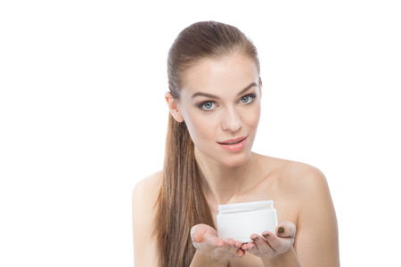 Fashion model holding a moisturizer or treatment, looking at the camera ,over a white backgroundの写真素材