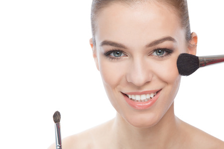 Woman smiling at hte camera, with make-up brushesの写真素材