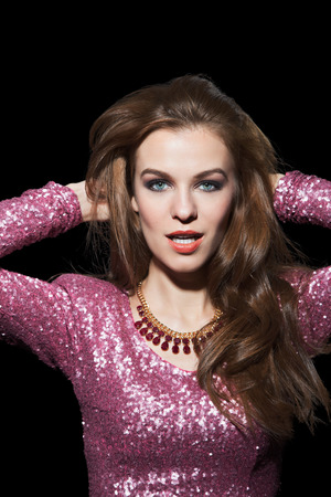 Portrait of a beautiful young woman in a pink party dress. Isolated on black background.の写真素材