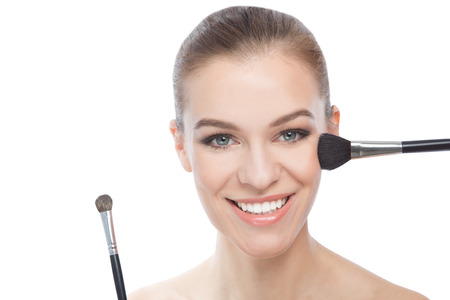 Smiling woman using make-up brushesの写真素材