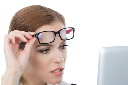 A studio portrait of a beautiful young woman wearing glasses looking at her laptop. Isolated on white. の写真素材