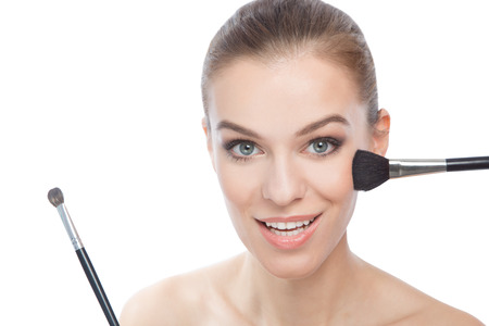 Smiling woman using make-up brushesの写真素材