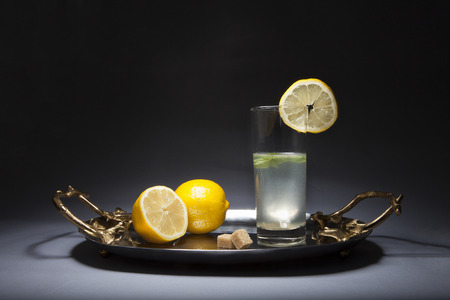 Glass fo lemonade on silver tray with golden handles on a dark backgroundの写真素材