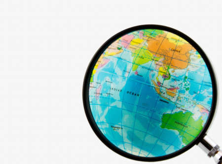 A magnifying glass view of a small colored globe isolated on a white backgroundの写真素材