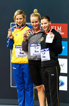 50m medalists pose for a group shot on the podium. Gold medalist: Jessica Hardy, silver: J. Johansson, bronze Dorothea Brandt. 2010 Fina Swimming World Cup. Singapore 17/10/2010.のeditorial素材