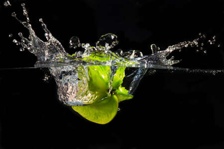 A falling star fruit plunges into the water creating a large splashの写真素材